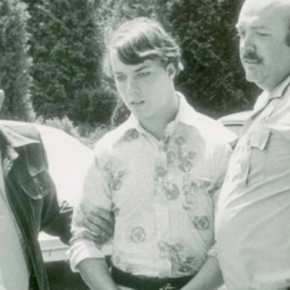 Black and white picture of Gene McGuire being taken into custody