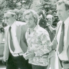 Black and white picture of Gene McGuire being taken into custody